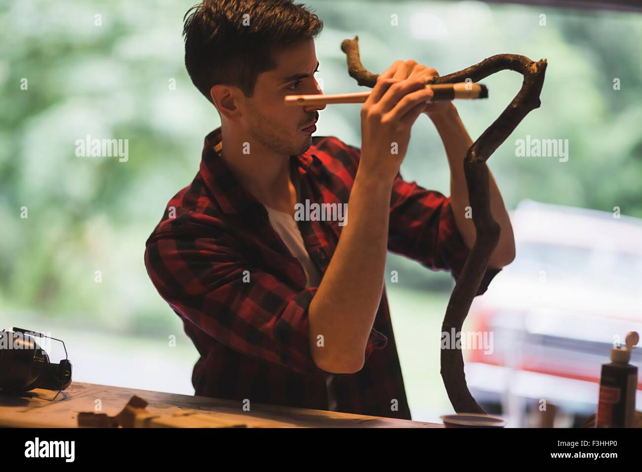 Junger Mann hält Pinsel malen Baumzweig Stockfoto