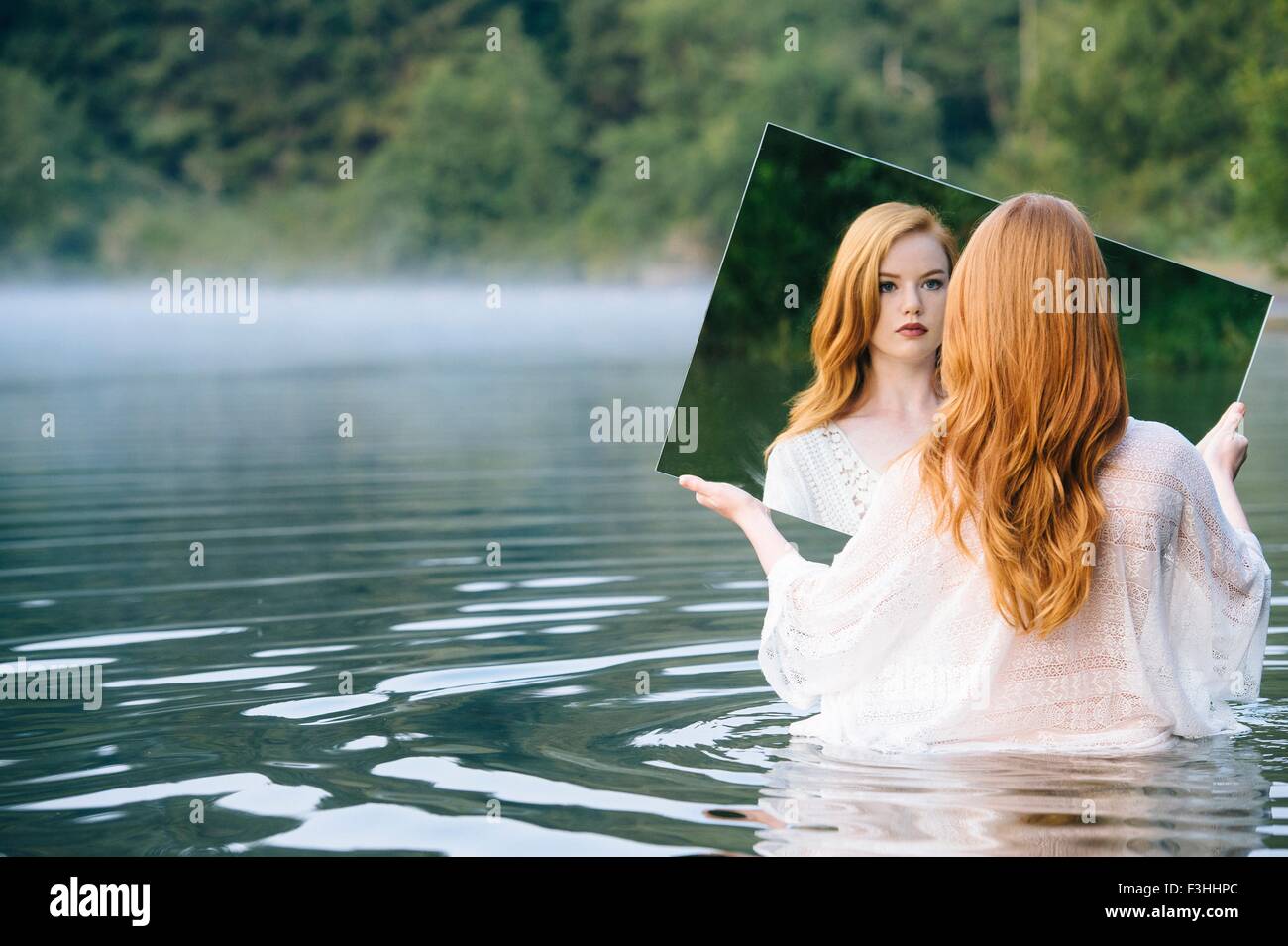 Rückansicht des jungen Frau im See mit Blick auf Reflexion Spiegel Stockfoto