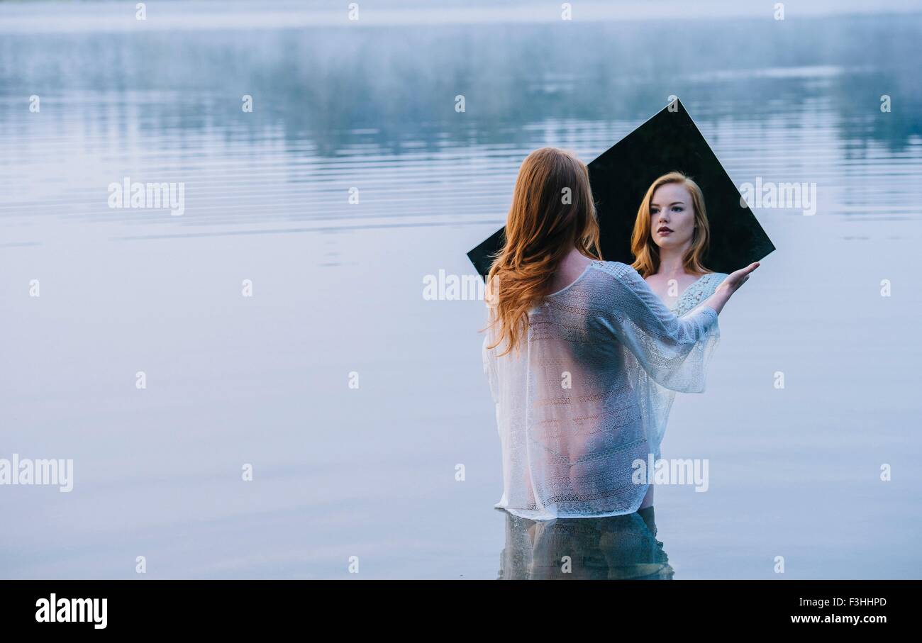 Rückansicht des jungen Frau im See mit Blick auf Reflexion Spiegel Stockfoto