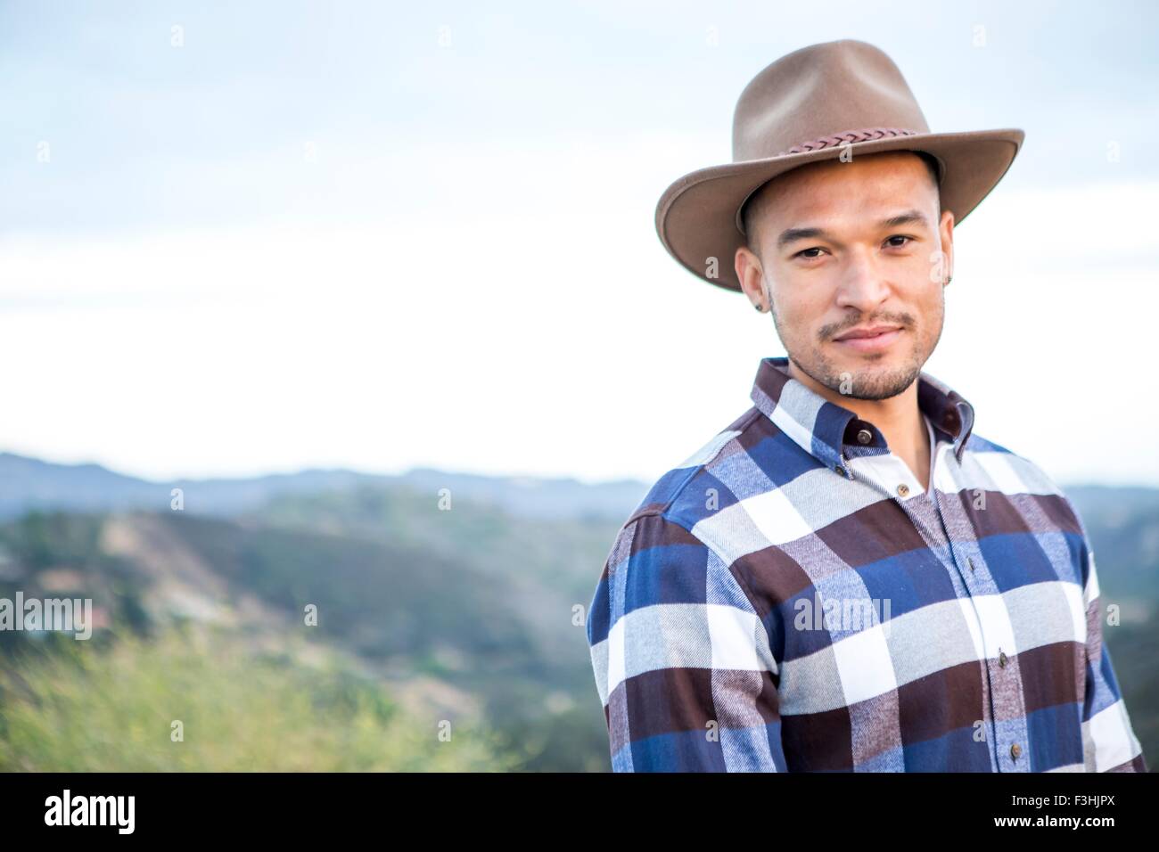 Porträt des jungen Mann mit Cowboyhut auf ländlichen Hügel Stockfoto