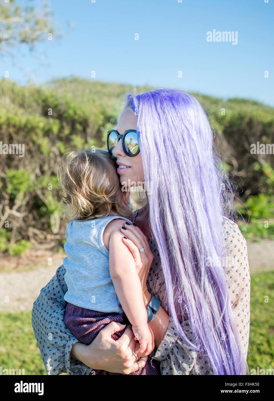 Junge Frau mit langen lila Haare, Baby Tochter hielt Stockfoto