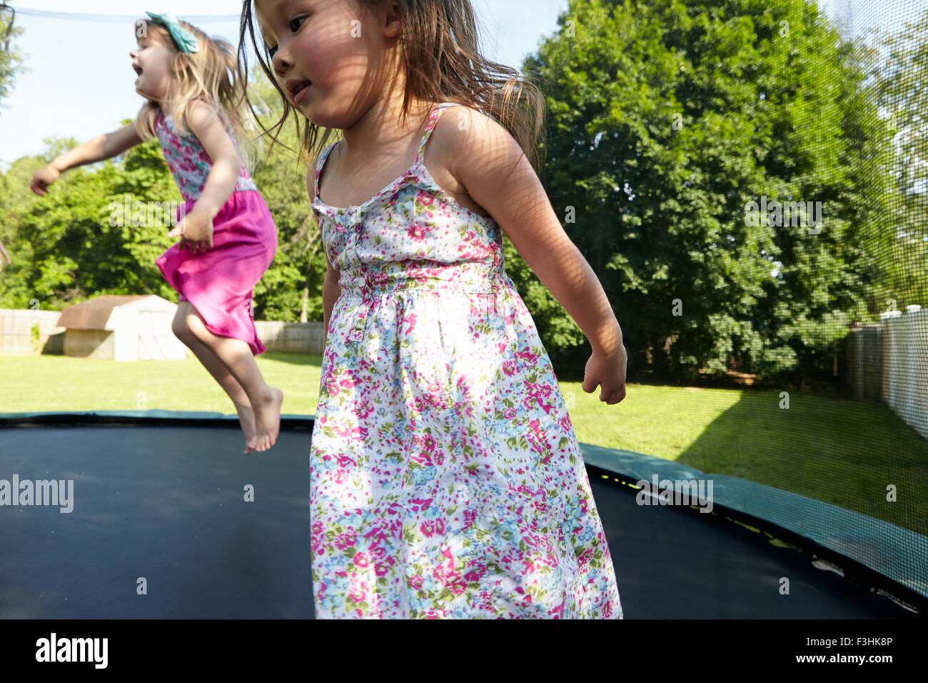 Zwei Mädchen springen auf dem Trampolin im Garten Stockfoto