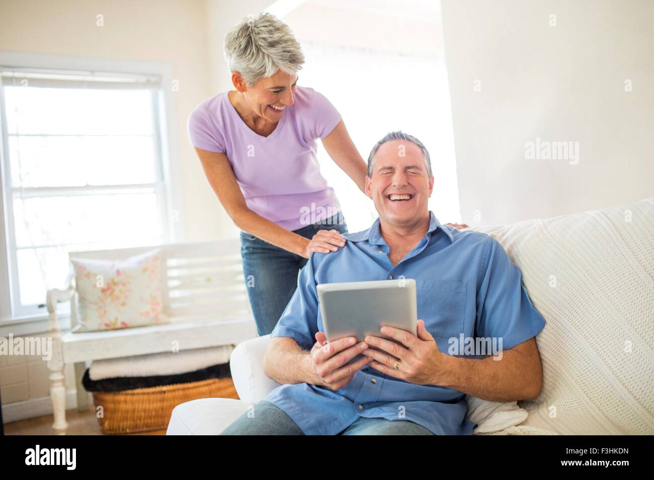 Reifen Sie paar lachen, während digitale Tablet benutzen Stockfoto