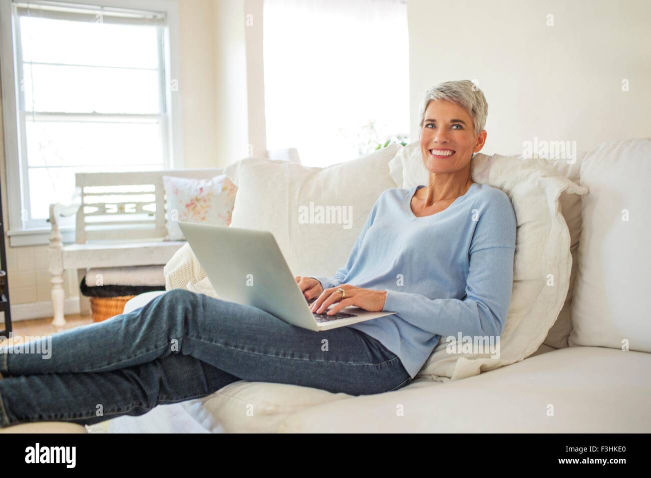 Porträt von Reife Frau liegend auf Sofa Tippen auf laptop Stockfoto