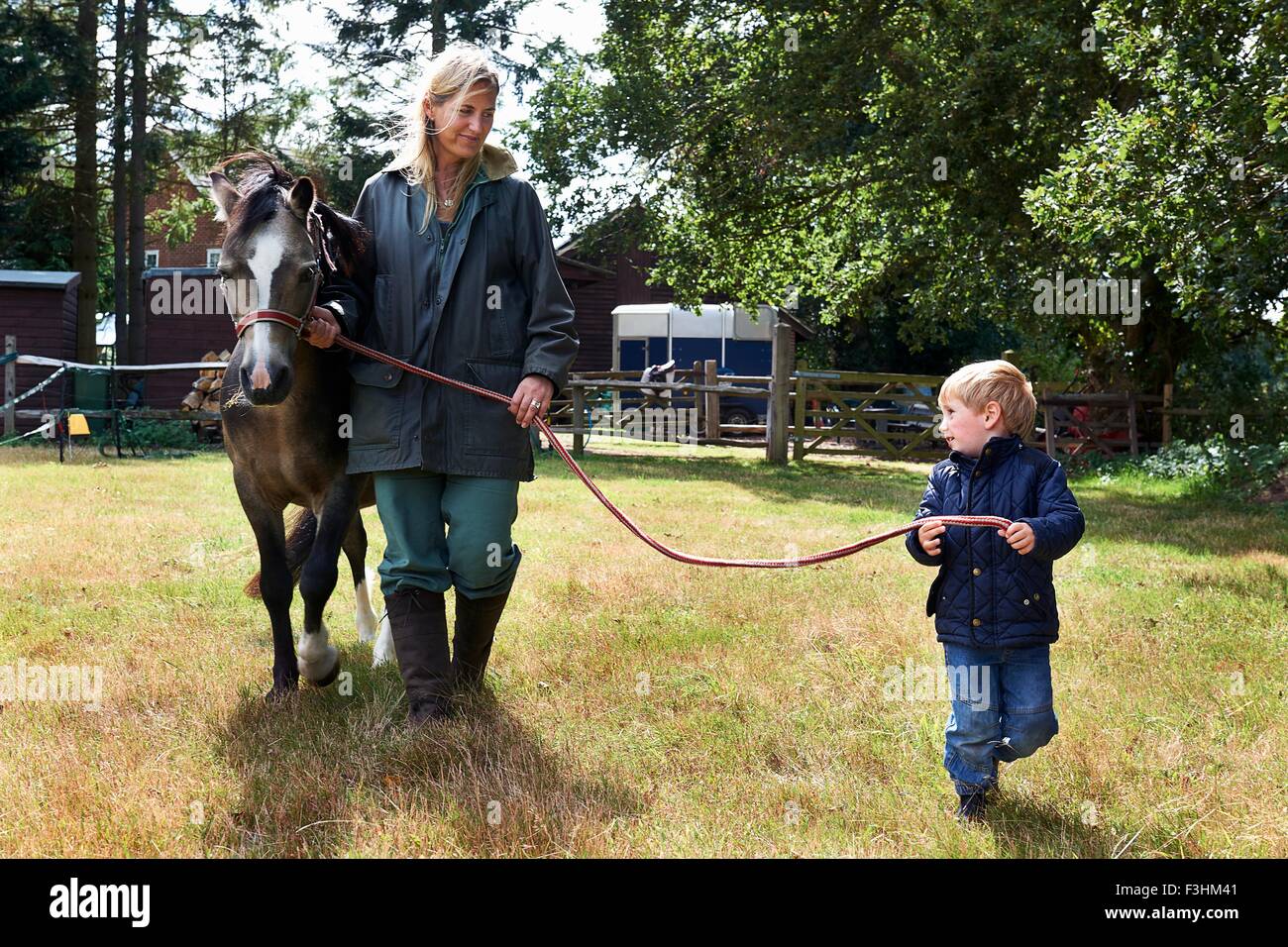 Kleiner Junge und Mutter führenden Pony im Feld Stockfoto Kleiner Junge und Mutter führenden Pony im Feld Stockfoto