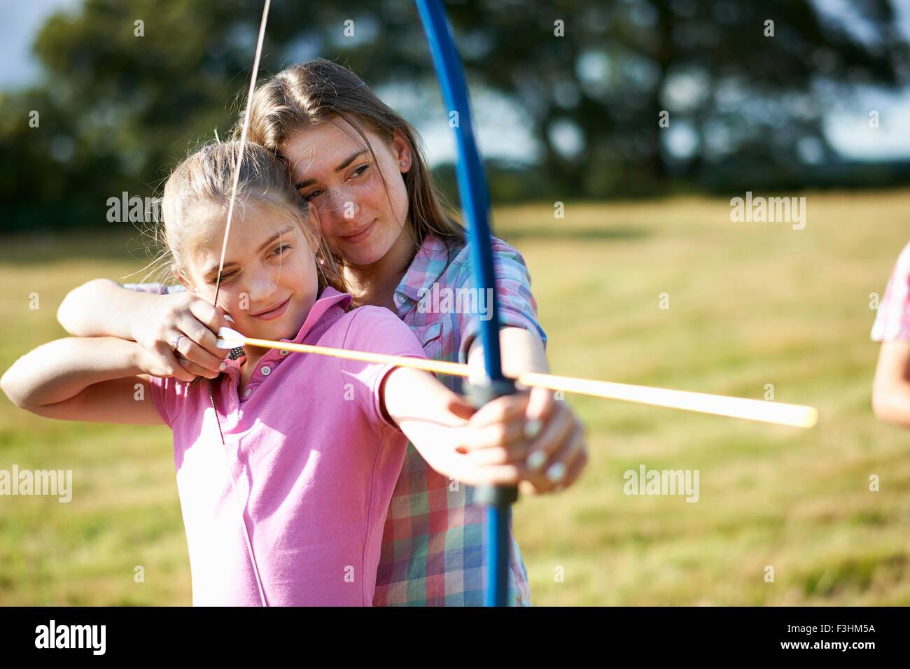 Mädchen lernen Bogenschießen von Teenager Schwester Stockfoto