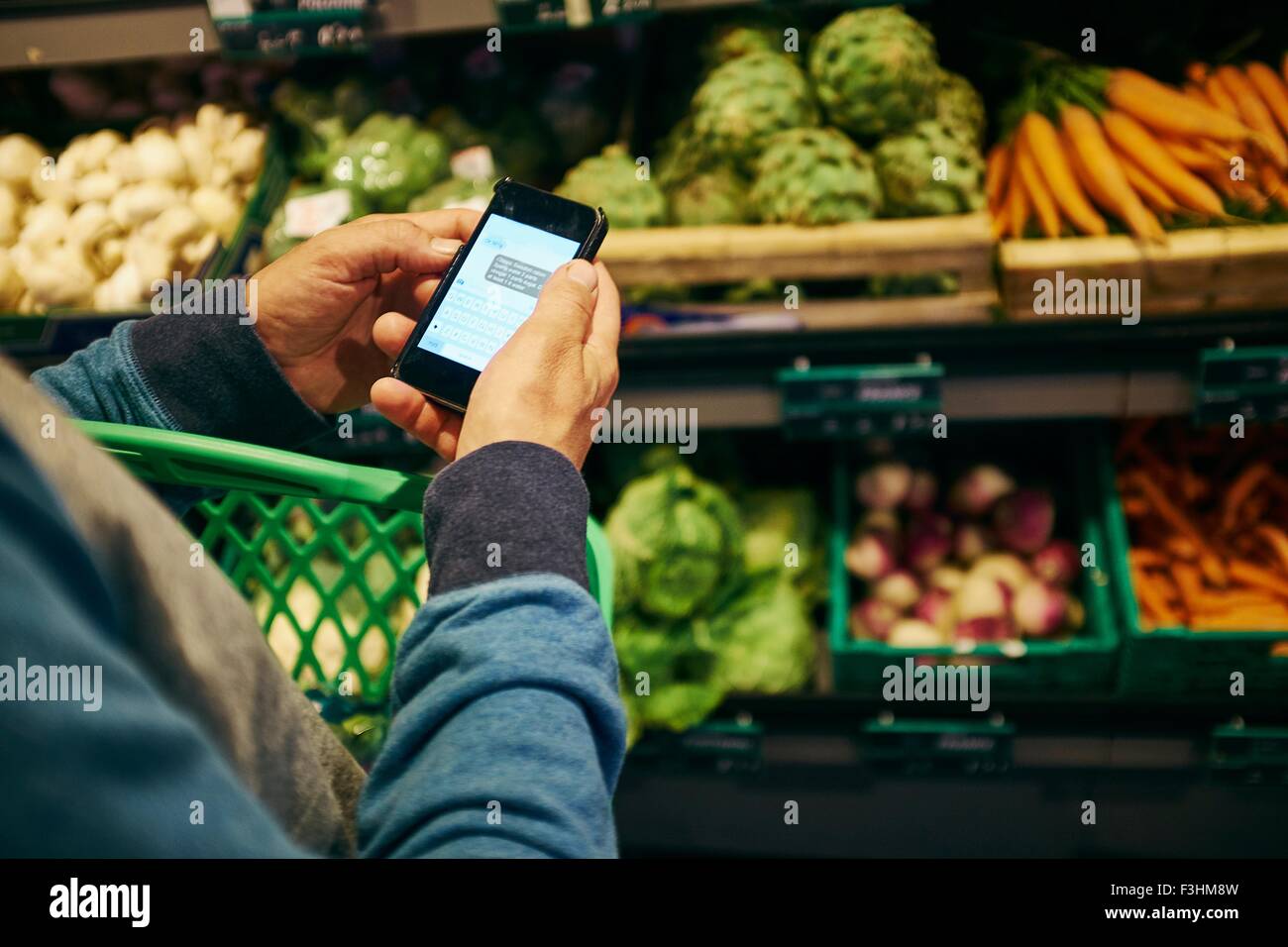 Mann einkaufen und mit Smartphone in Supermarkt Stockfoto