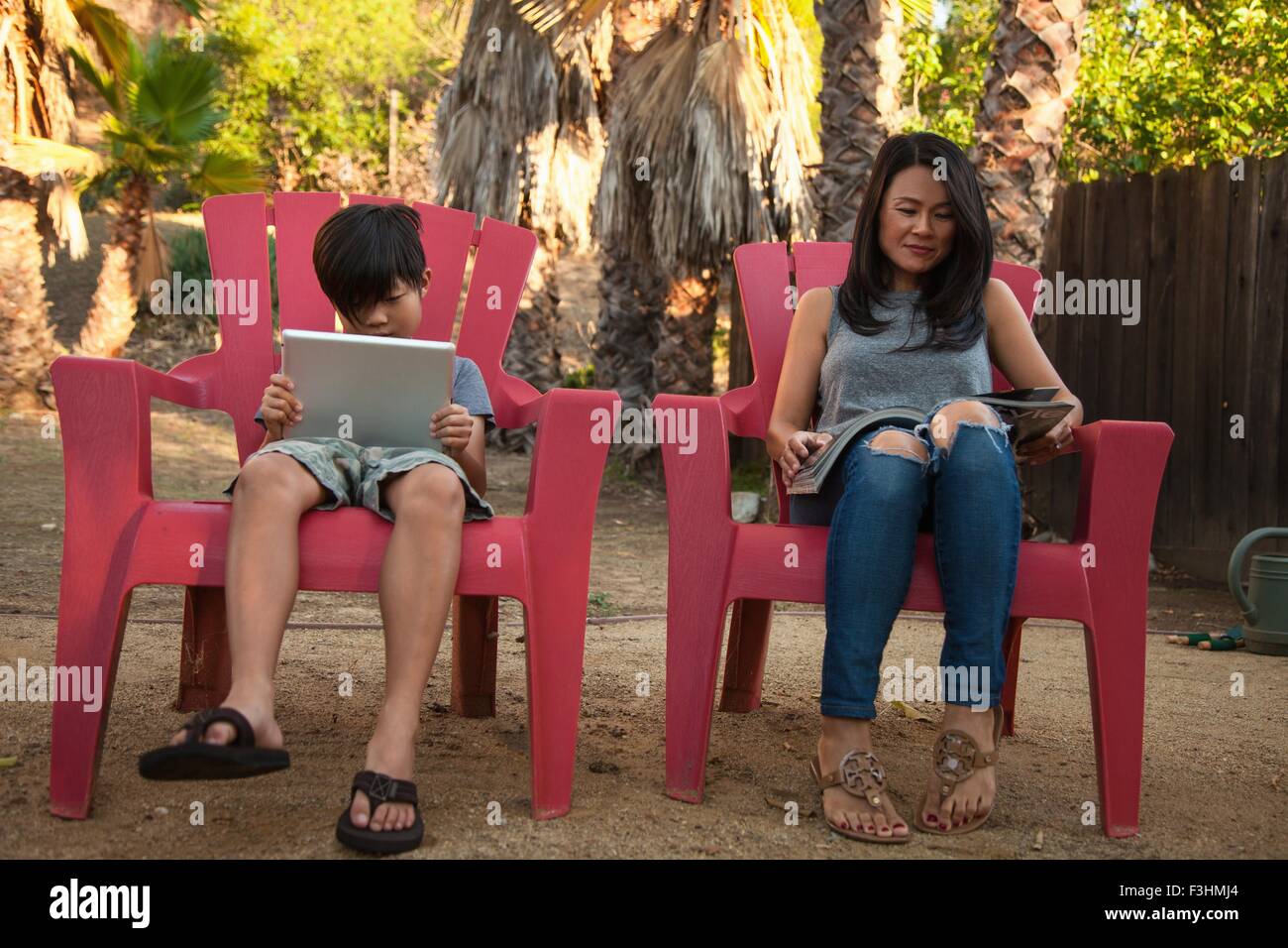 Junge und Mutter lesen digital-Tablette und Magazin im Garten Stockfoto