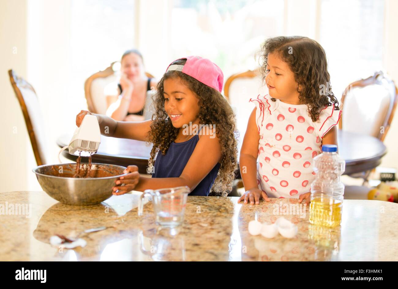 Schwestern am Küchentisch Quirlen Choclate Cake mix in Rührschüssel blickte lächelnd Stockfoto