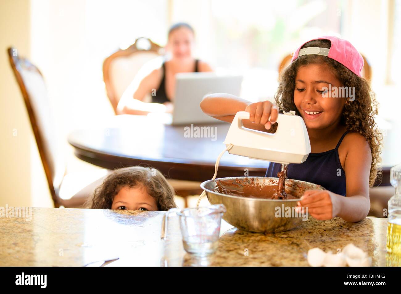 Schwestern schlagen Schokoladenkuchen mischen in die Rührschüssel geben, Lächeln Stockfoto