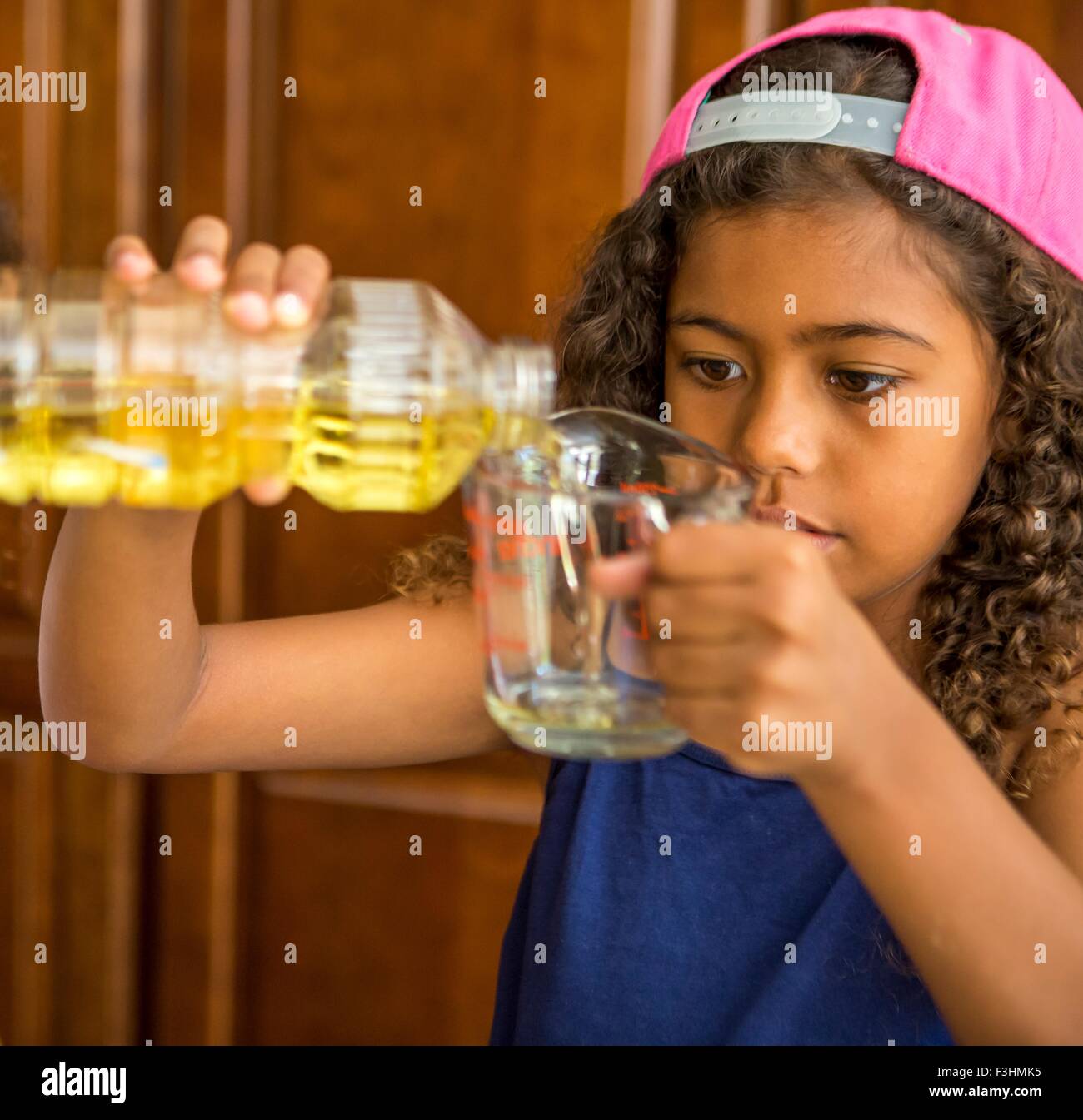 Mädchen, Gießen Speiseöl in Messung Krug Stockfoto