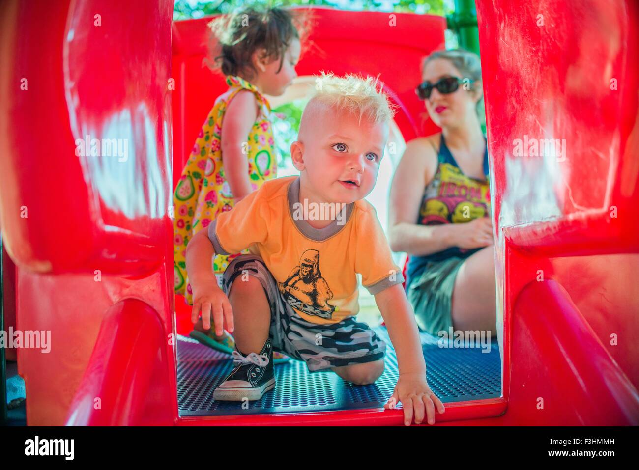 Mutter und Kinder spielen am roten Rutschbahn Stockfoto