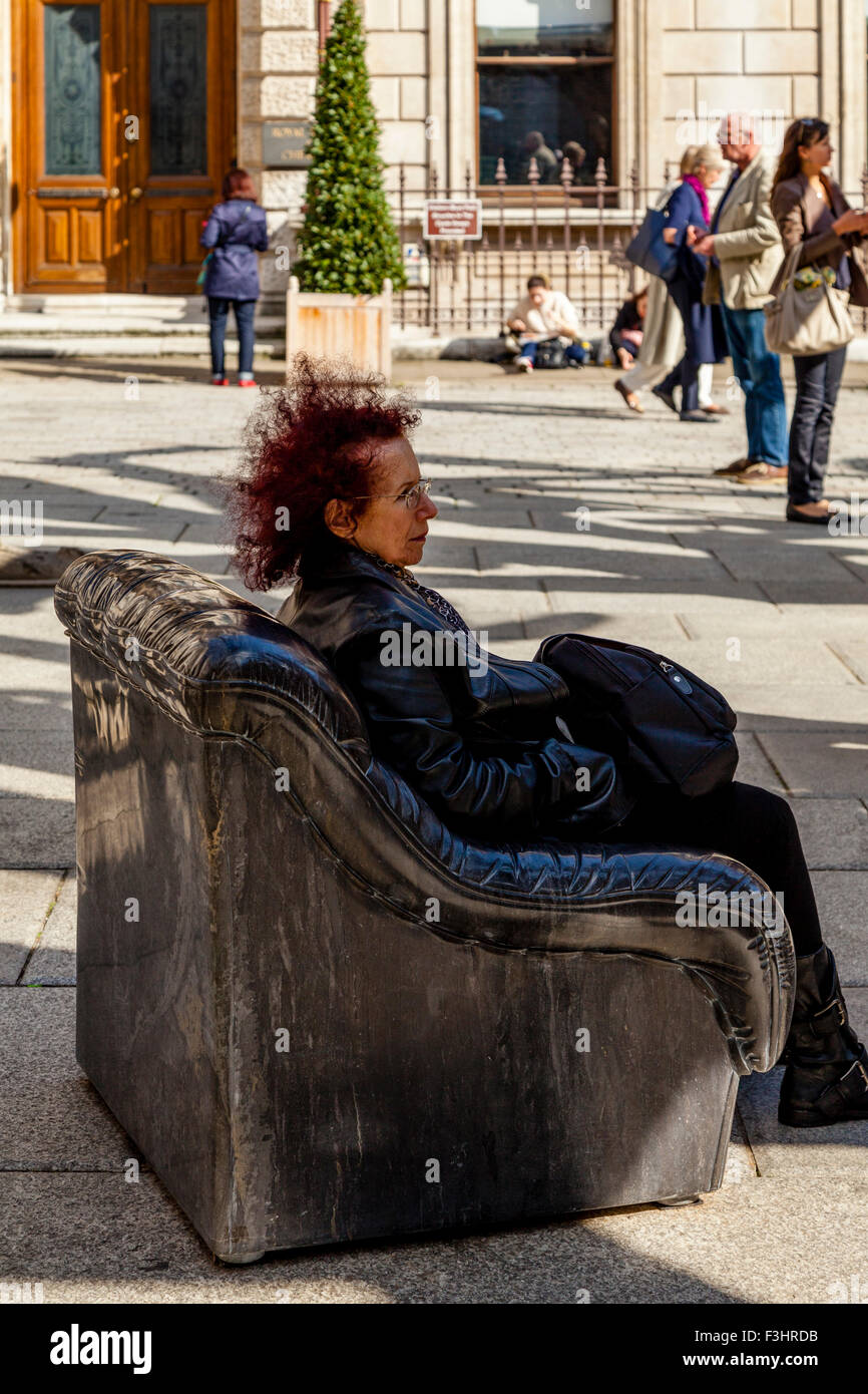 Eine Frau sitzt auf einem Marmor Stuhl, Teil des Ai Weiweis Baum Installation an der Royal Academy of Art, London, England, UK Stockfoto