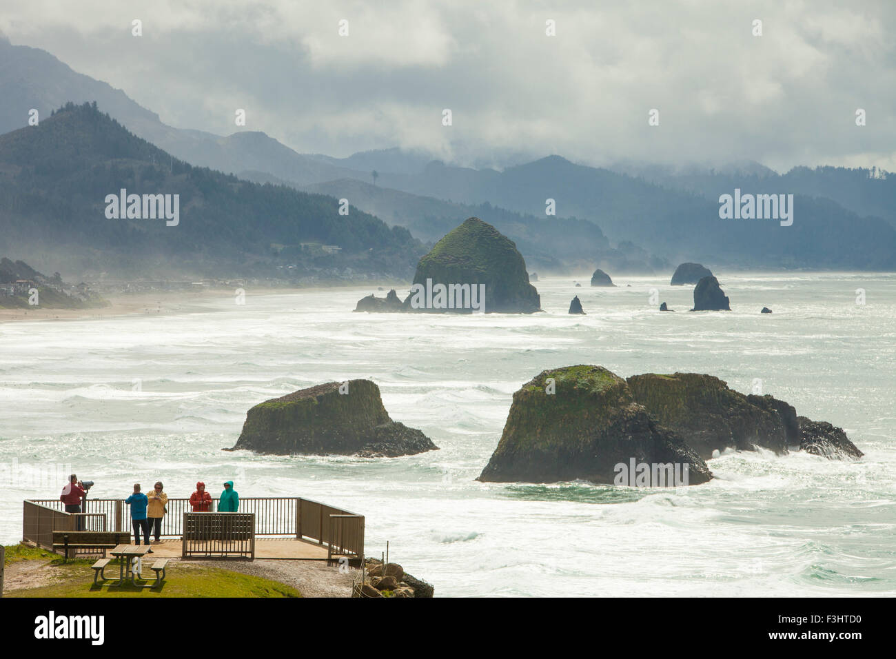 Touristen genießen den Blick auf Haystack Rock und Cannon Beach von einem Aussichtspunkt in Ecola State Park, Oregon. Stockfoto
