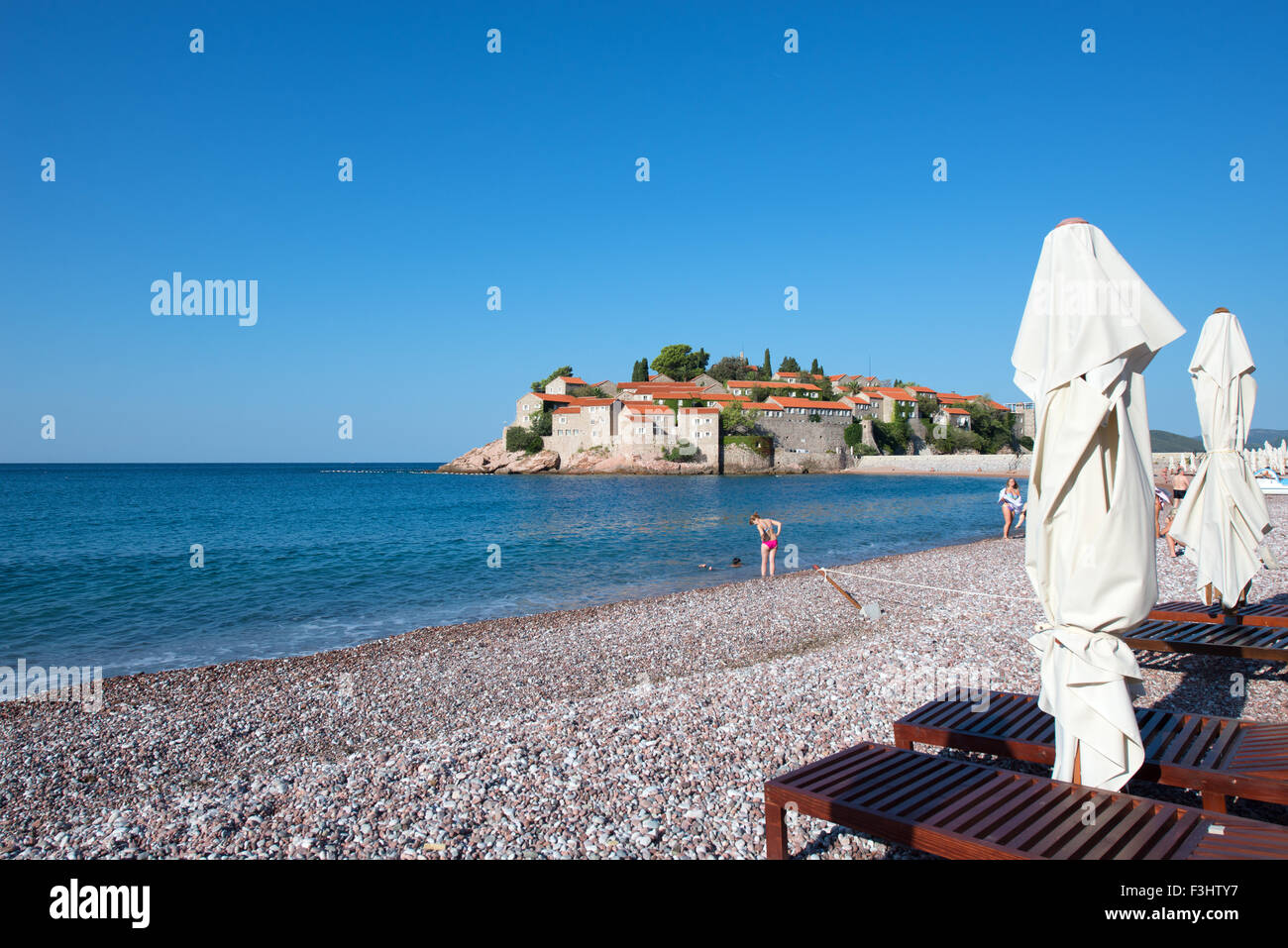 Sonne und Strand Sonnenschirme vor Insel und Hotel Resort Sveti Stefan (St. Stephan), Montenegro Stockfoto