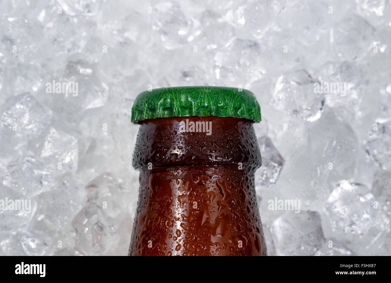 Nahaufnahme von einer einzigen teilweise Flasche Bier Kappe auf Haufen von Eis abkühlen. Layout im Querformat. Stockfoto