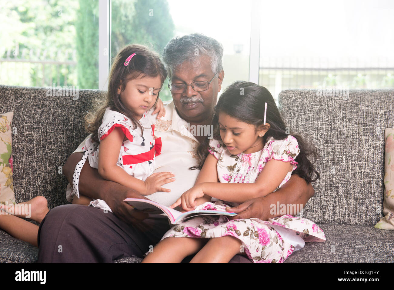 indische Großvater lernen mit seinen Enkelinnen Stockfoto