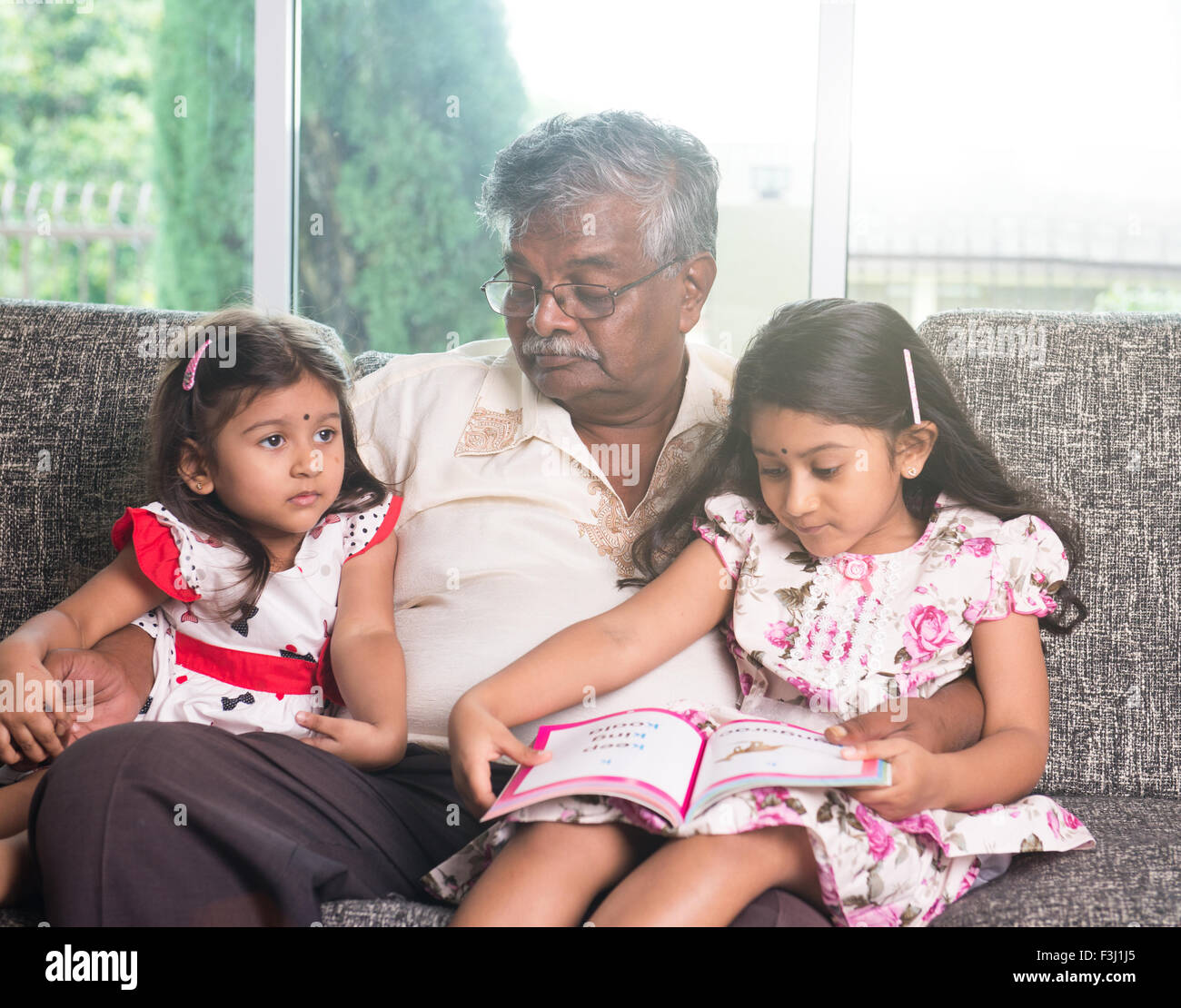 indische Großvater lernen mit seinen Enkelinnen Stockfoto