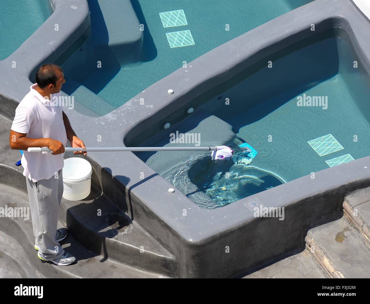 Ein Hotel-Arbeiter mit einem Kokido Skooba Vac einige Tauchbecken auf der Insel Santorini Griechenland sauber Stockfoto