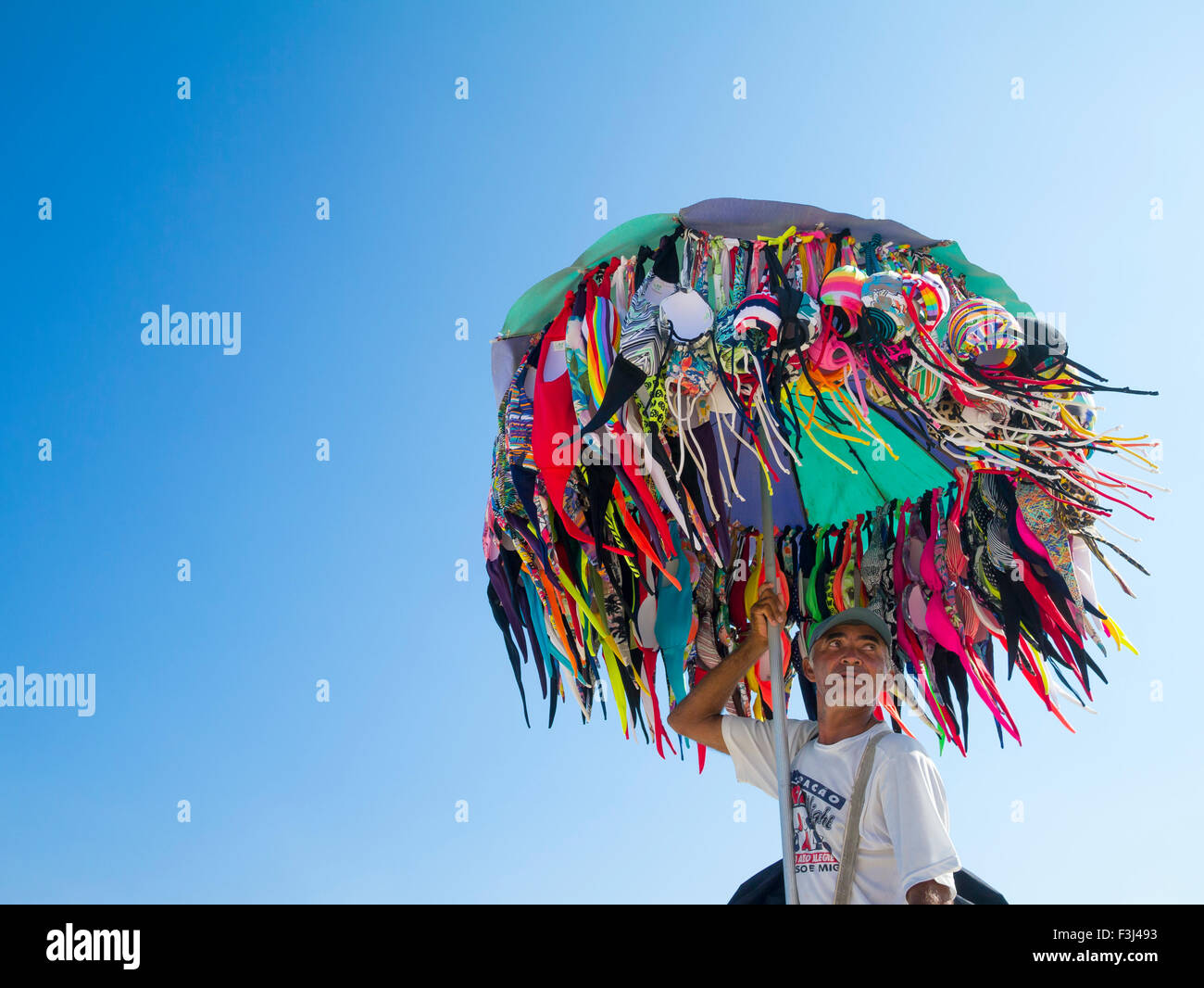 RIO DE JANEIRO, Brasilien - 22. Januar 2014: Strand Verkäufer verkaufen Bikinis trägt seine Ware in einem Sonnenschirm in Ipanema. Stockfoto
