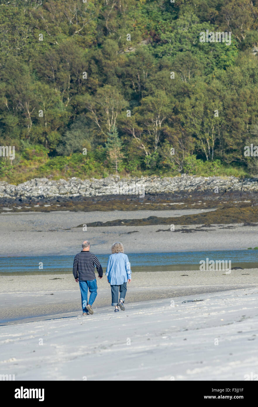 Mann und Frau zu Fuß entlang der weißen Sandstrand Morar auf der Küste von North West Schottland. Stockfoto