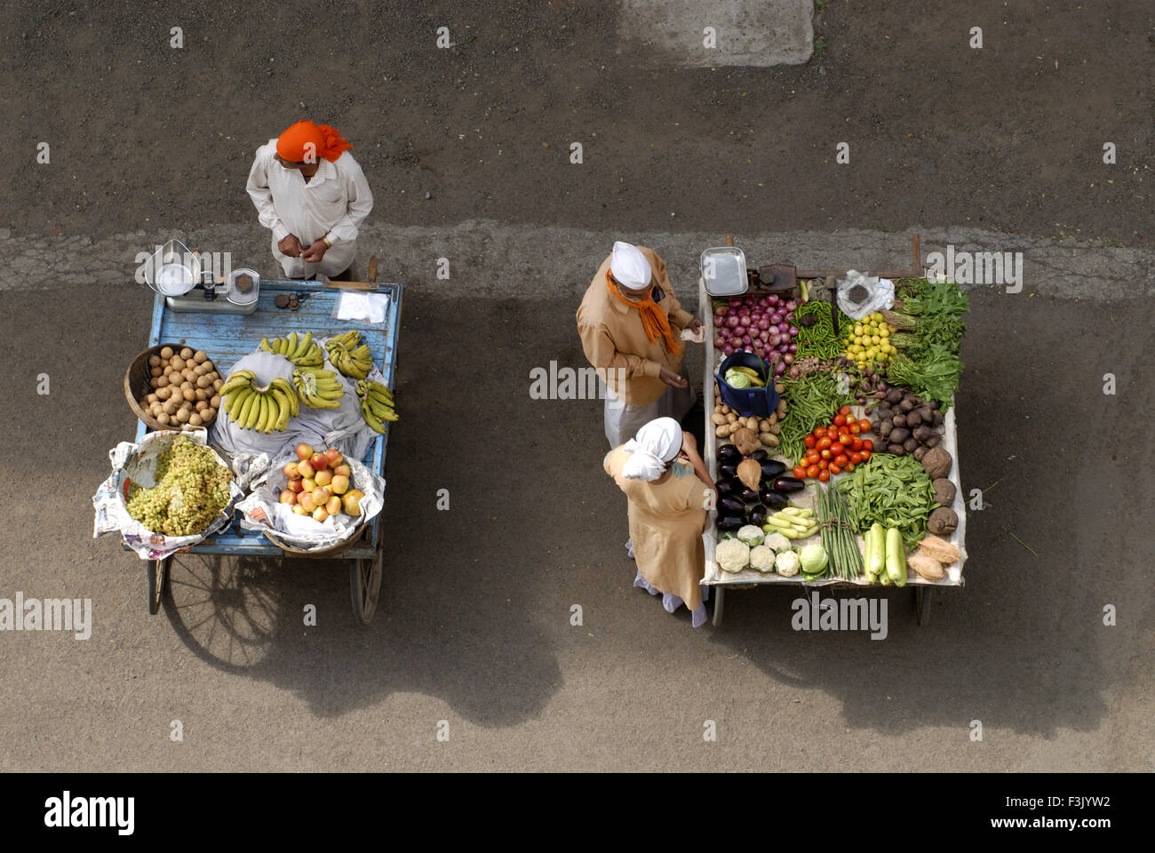 Luftaufnahme von zwei Handkarren und zwei Verkäufern ein mit verschiedenen Früchten und anderen mit Gemüse eine Frau Käufer bei Pune Maharashtra india Stockfoto