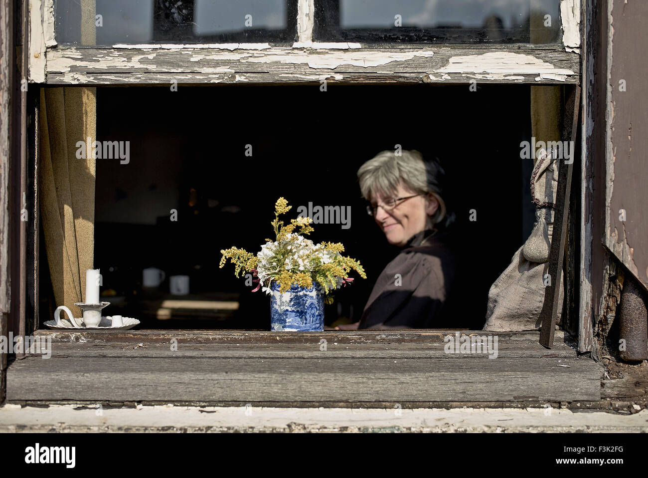 Frau, die aus dem Fenster in ihrem Haus schaut. Black Country Living Museum Dudley West Midlands England Großbritannien Stockfoto