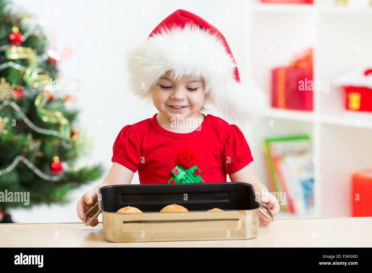 Kind Mädchen in Nikolausmütze halten Weihnachtsplätzchen Stockfoto