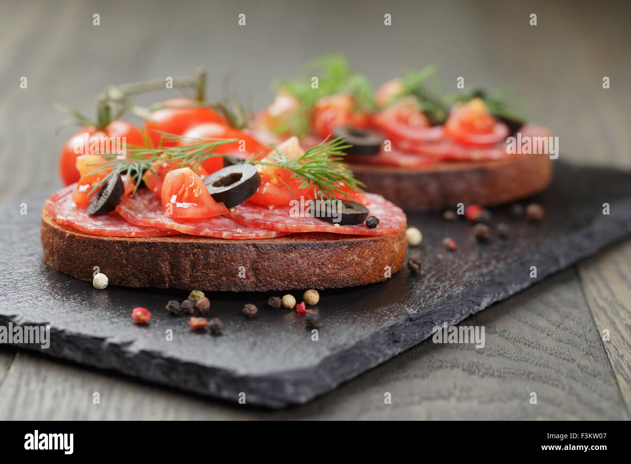 Roggen-Sandwich mit Salami und Tomaten auf Holztisch Stockfoto