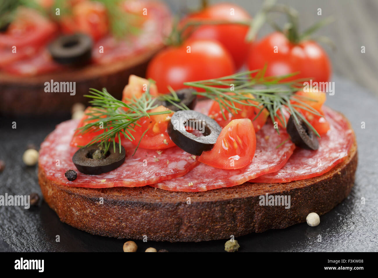 Roggen-Sandwich mit Salami und Tomaten auf Holztisch Stockfoto