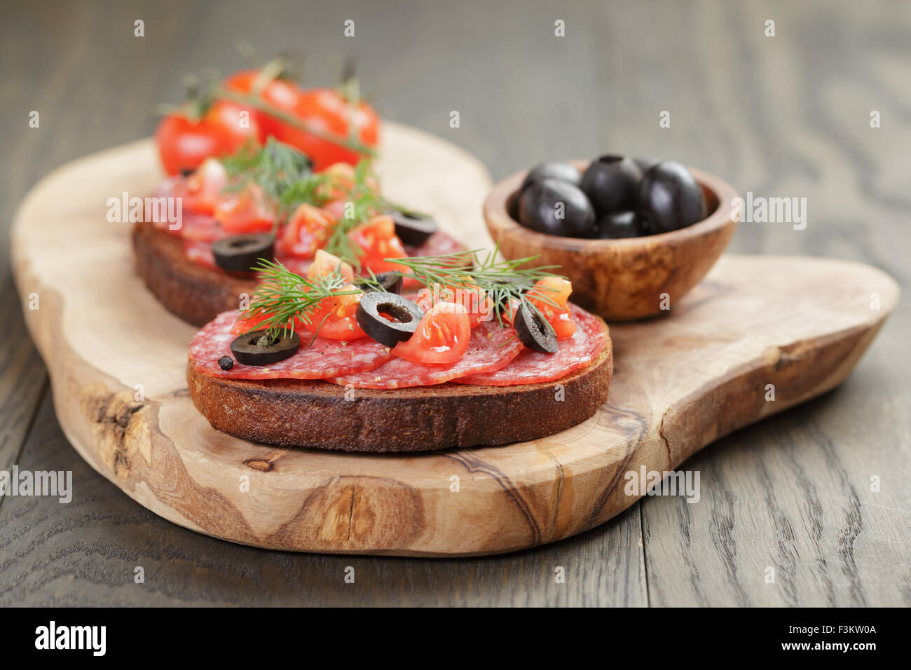 Roggen-Sandwich mit Salami und Tomaten auf Holztisch Stockfoto