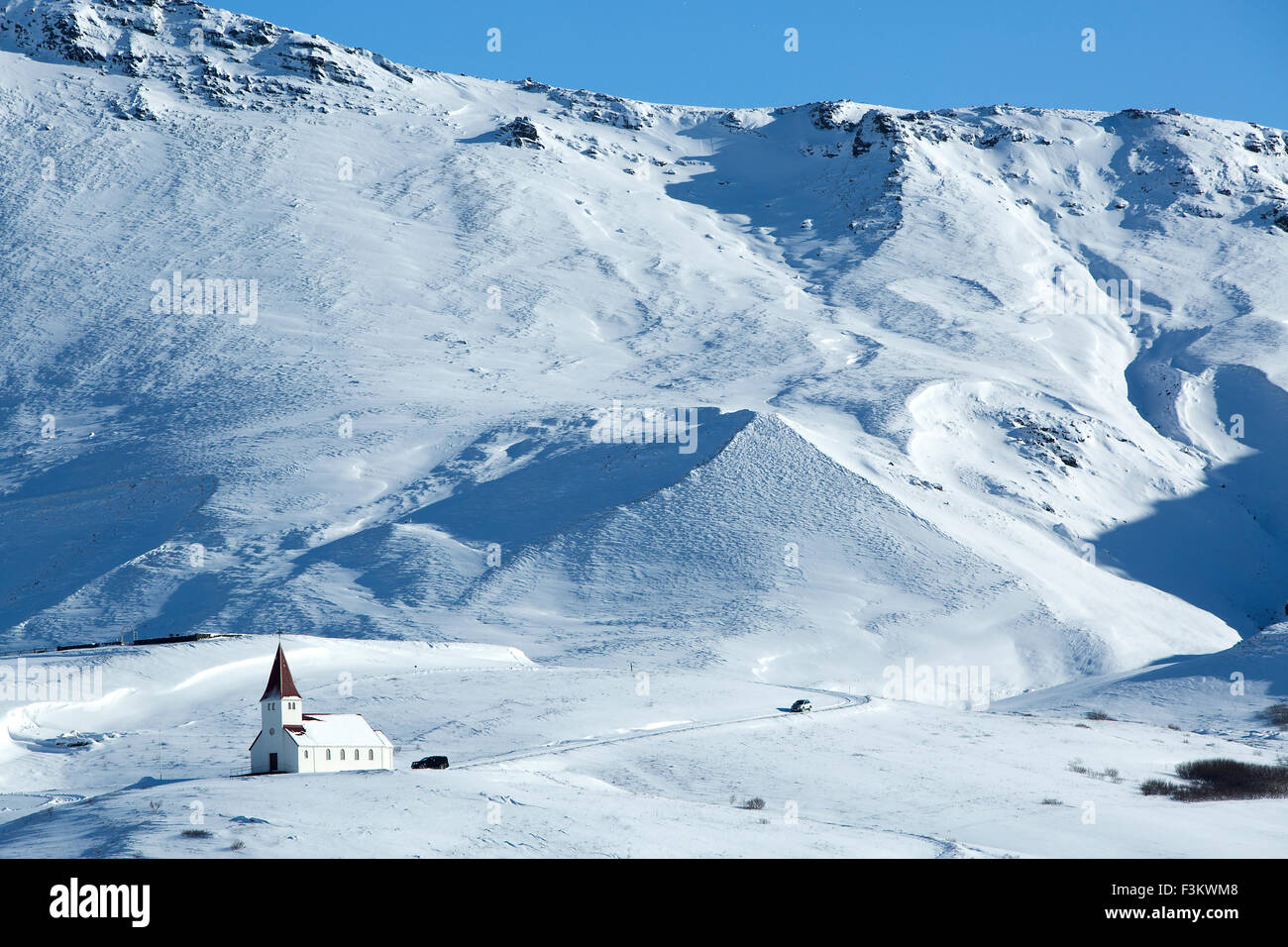 Kirche von Vik im Winter mit verschneiten Bergen, Island Stockfoto