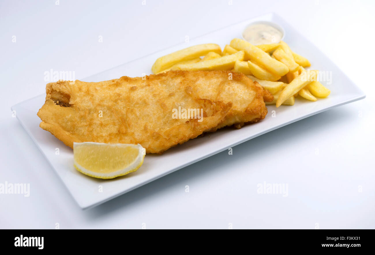 Isolierte Fish And Chips mit einem Keil von Zitrone und Remoulade auf einem weißen Teller Stockfoto