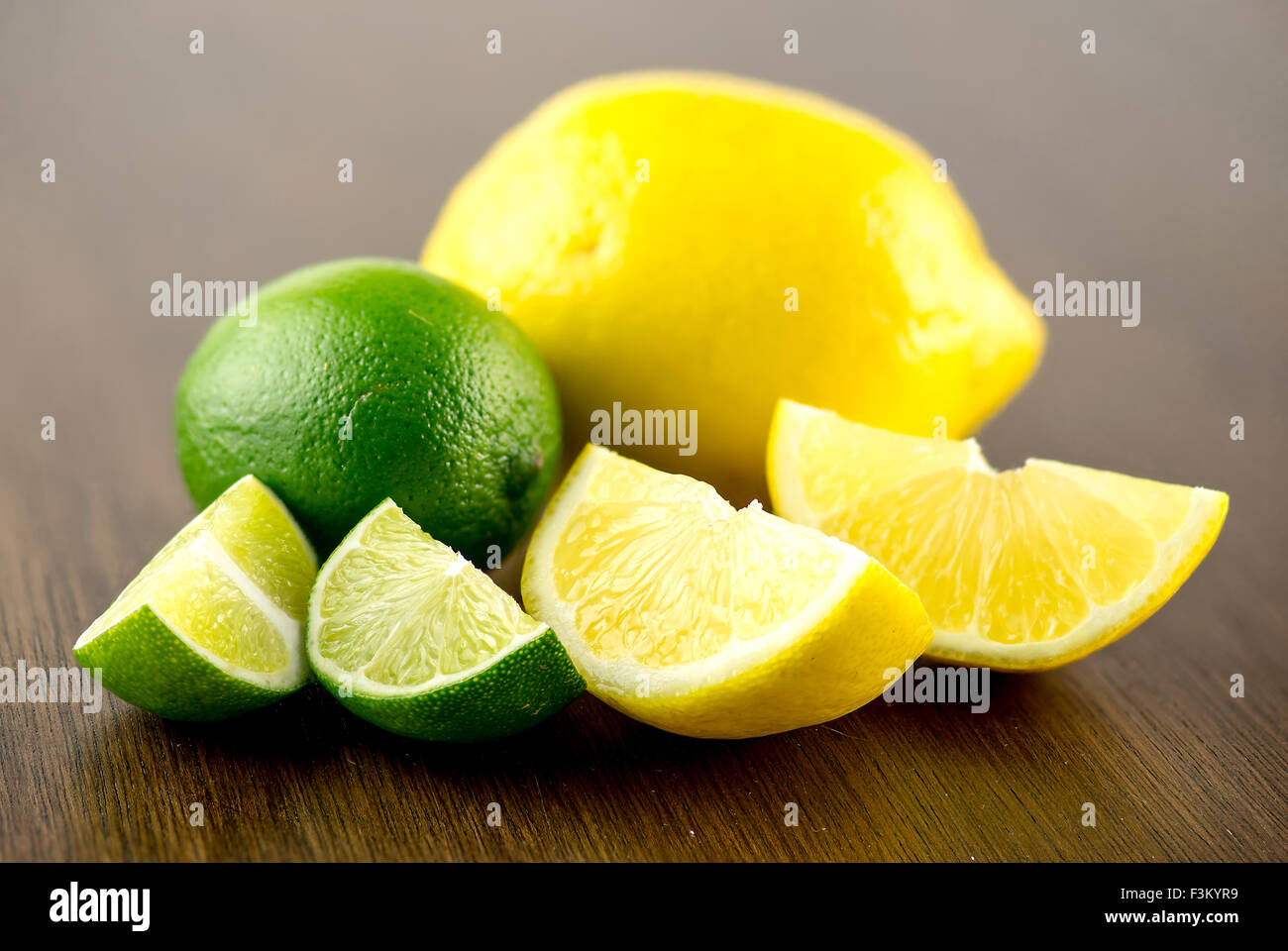 Makro Nahaufnahme von Limette und Zitrone Keile mit ganzen Früchten dahinter Stockfoto