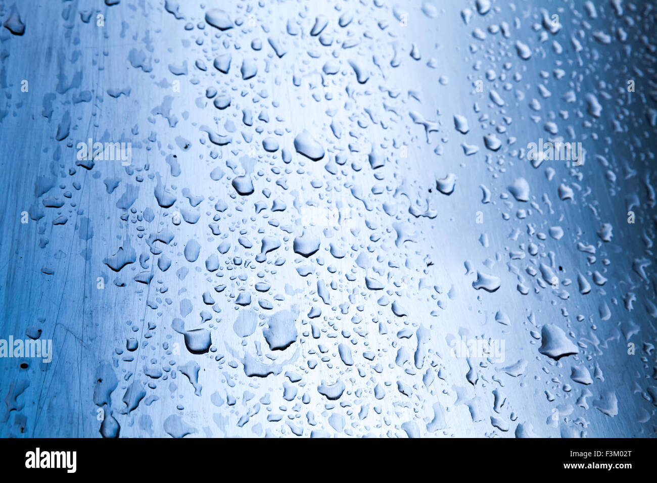 Gebogene Edelstahl-Oberfläche mit Wasser Tropfen, blau getönten Foto mit selektiven Fokus Stockfoto