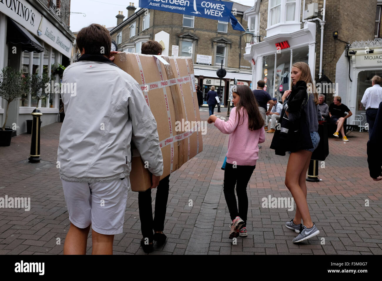 Männer großen Verpackung zu tragen, während Leute auf Yacht Racing schauen, Shore Seite Unterhaltungen, Bands, Yachtclub Szenen, 2015, Cowes Week, Isle Of Wight, England, UK, Stockfoto