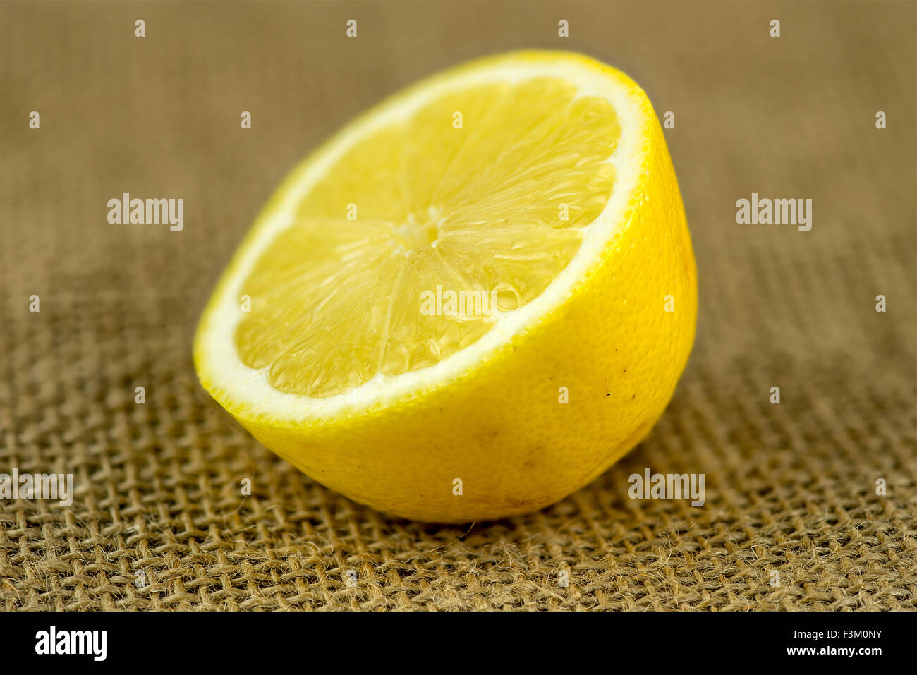 Extreme Makro Nahaufnahme der zerschnittenen Zitrone auf Sackleinen Hintergrund Stockfoto