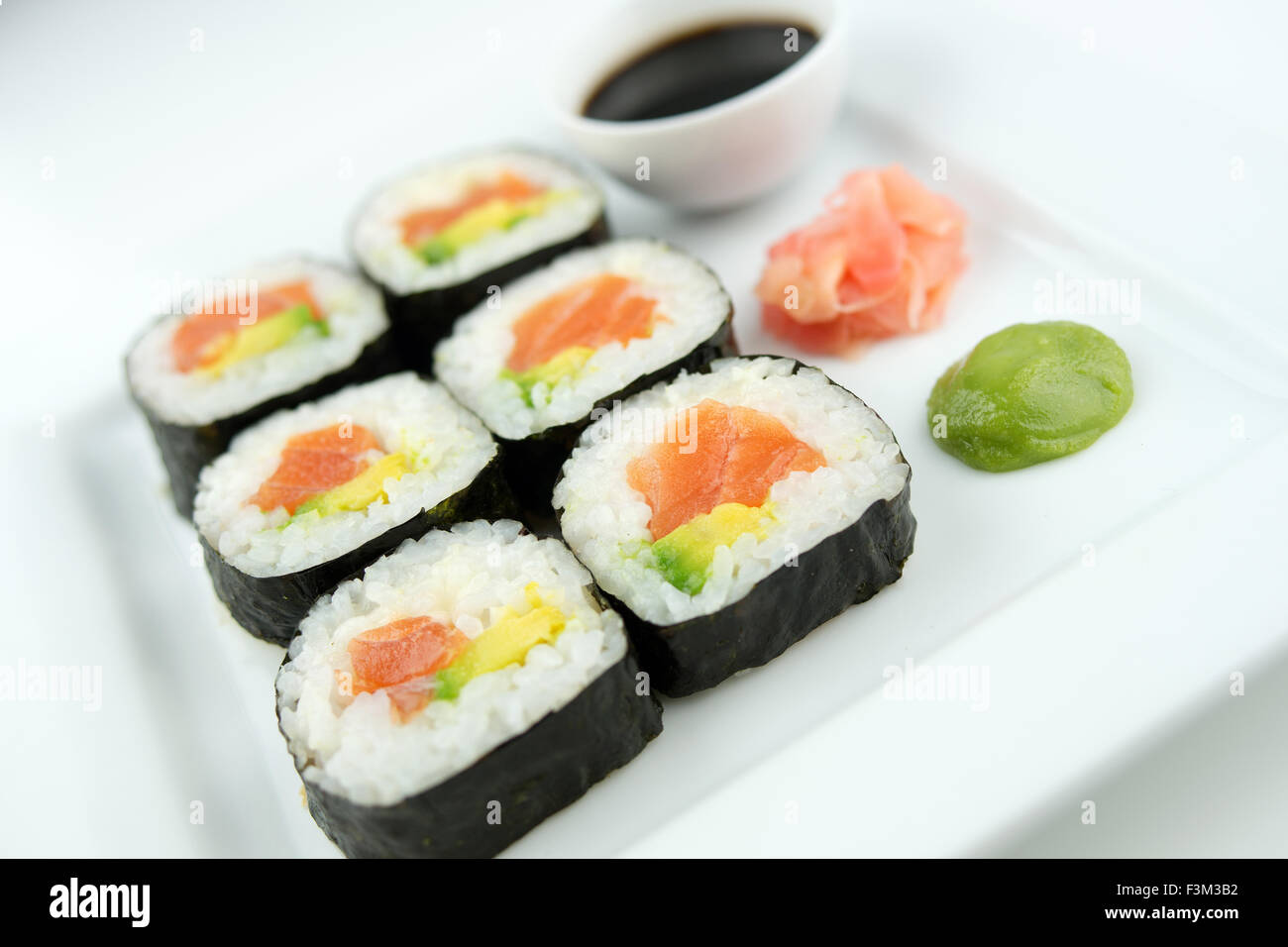 Frisch geschnittenen Lachs Sushi-Rollen auf einem weißen Teller mit Sojasauce, Wasabi und eingelegtem Ingwer Stockfoto