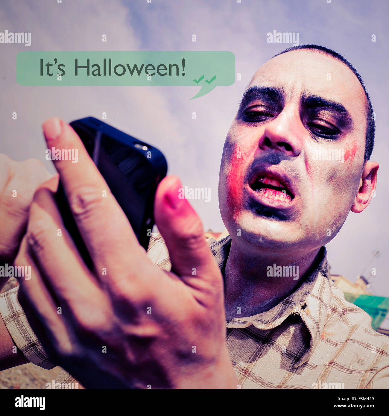 Nahaufnahme eines beängstigend Zombies senden oder empfangen einer SMS-Nachricht in sein Smartphone mit dem Text ist es halloween Stockfoto