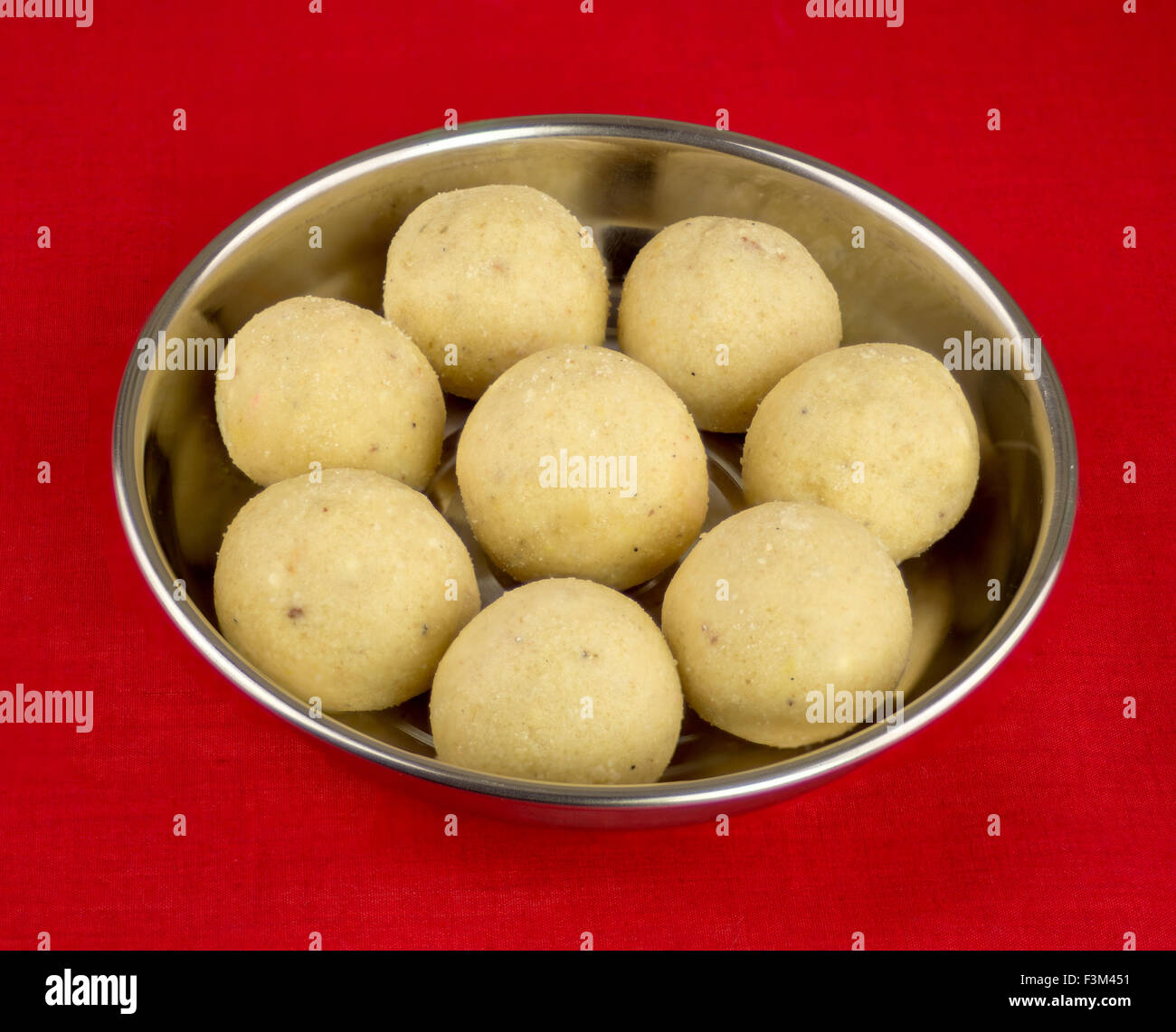 Indische Laddoo (Laddu) Süßigkeiten auf Silberplatte sitzt auf einer roten Tischdecke serviert. Stockfoto