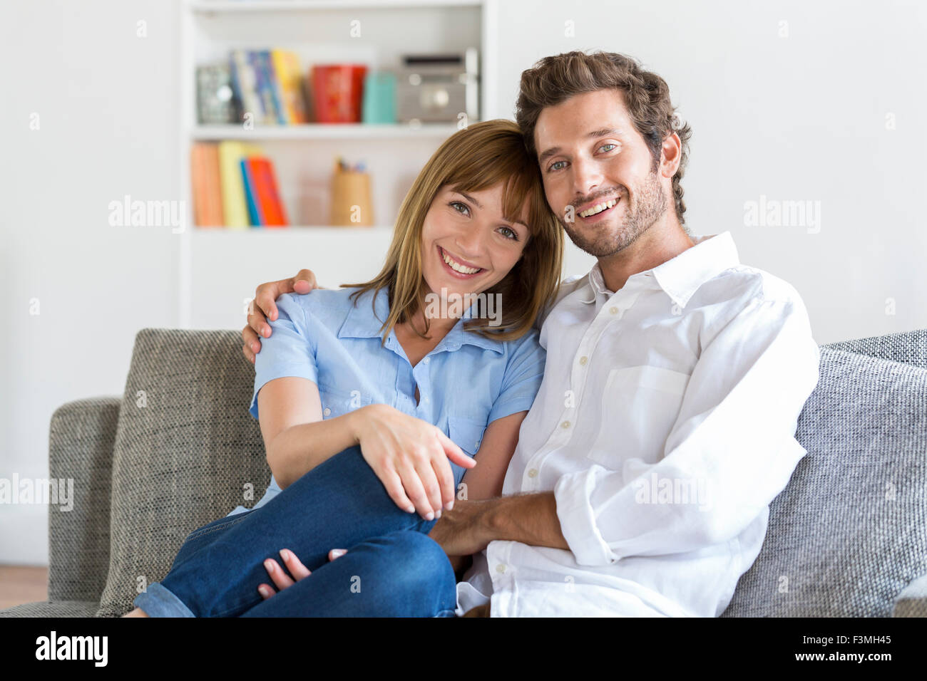 Porträt von fröhlichen dreißig Jahre alte Paar sitzt auf Sofa im modernen Ferienwohnung Stockfoto