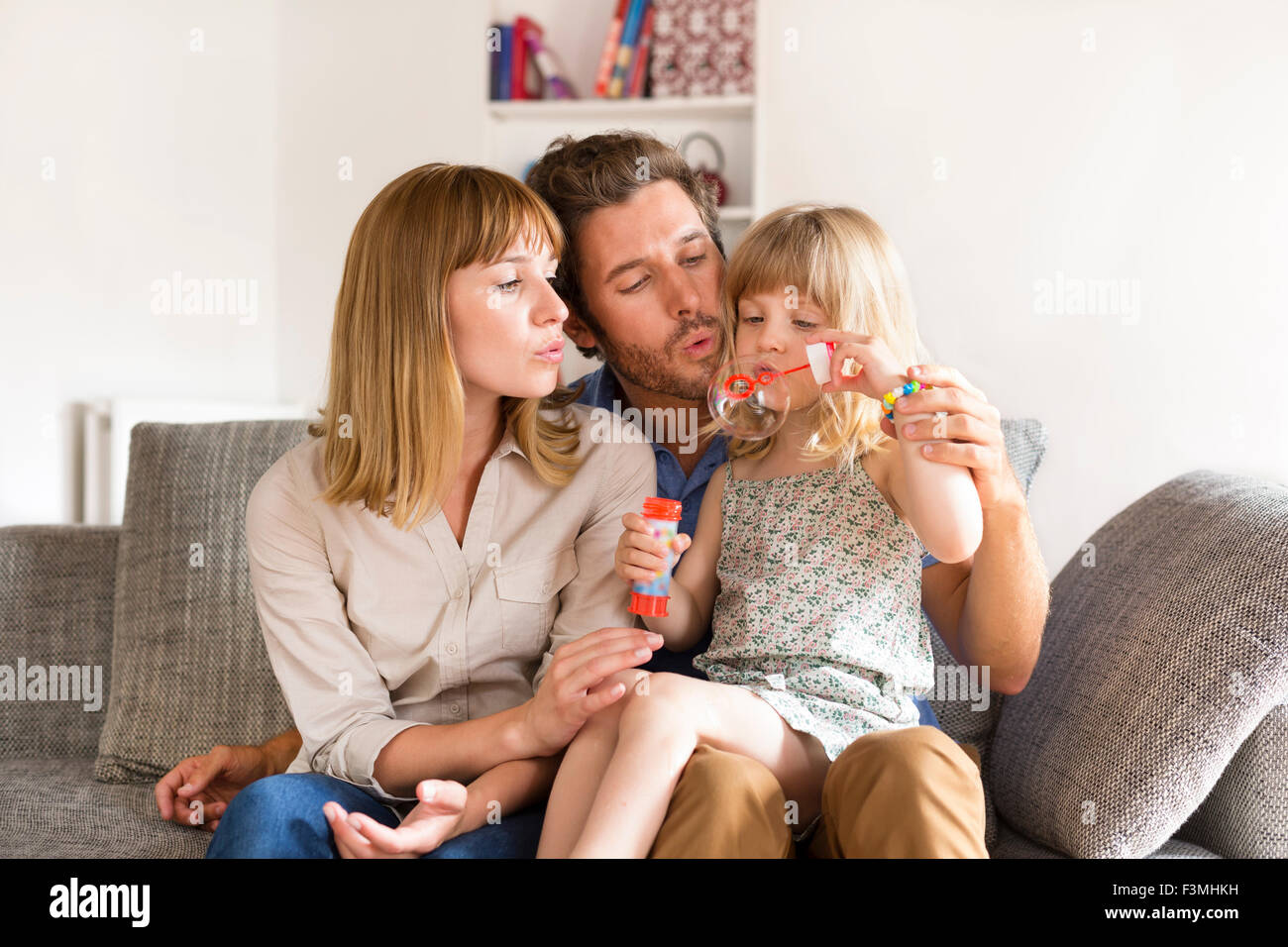 Fröhliche Eltern und Tochter Seifenblasen in weißen modernen Haus Stockfoto