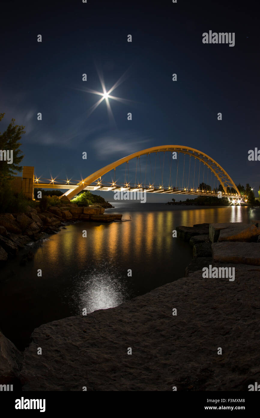 Beleuchtete Brücke in der Nacht mit einer Mondsichel. Stockfoto