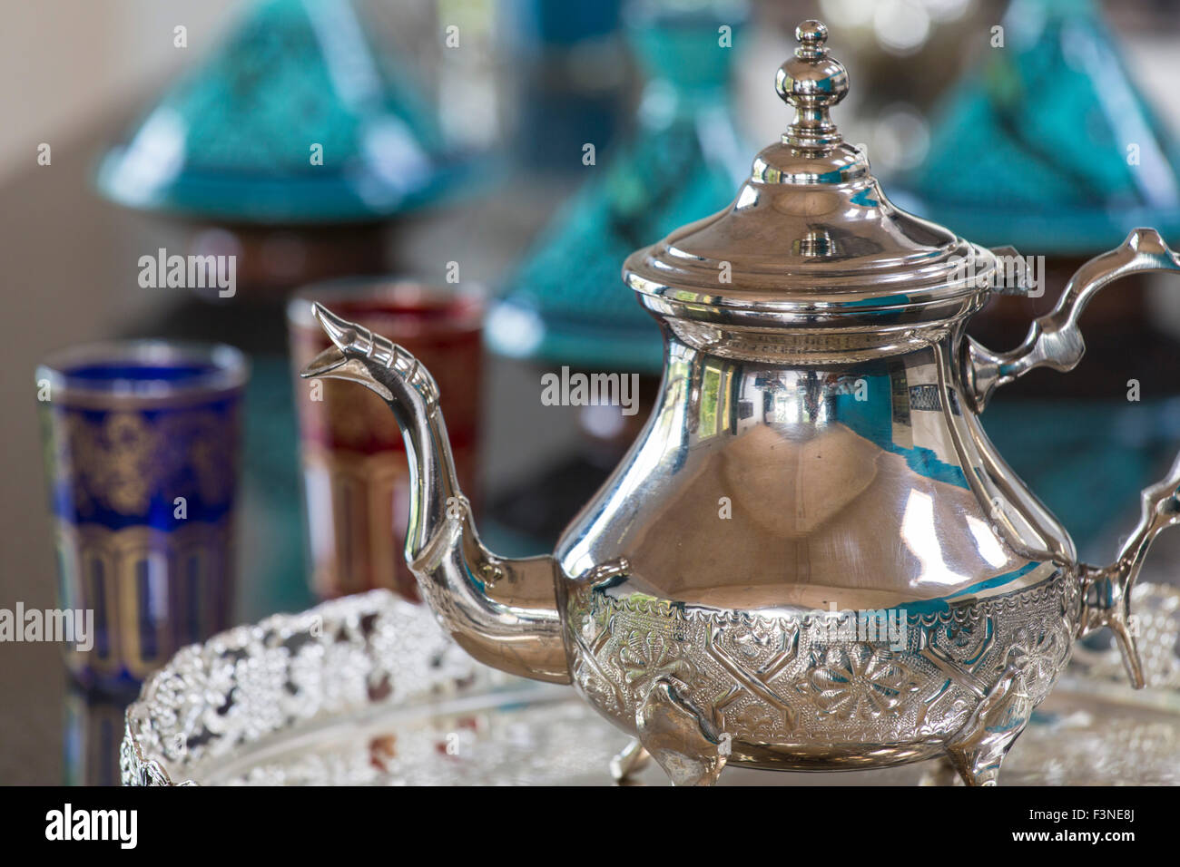 Marokkanische Teekanne mit Brille und Tagines im Hintergrund Stockfoto