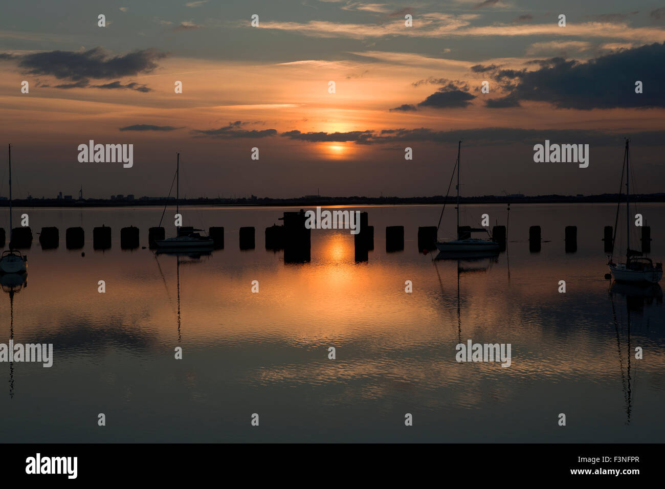 Sonnenuntergang auf der Hayling Billy-Brücke. Blick über Langstone Hafen in Richtung der untergehenden Sonne hinter Portsmouth auf einen ruhigen Abend. Stockfoto