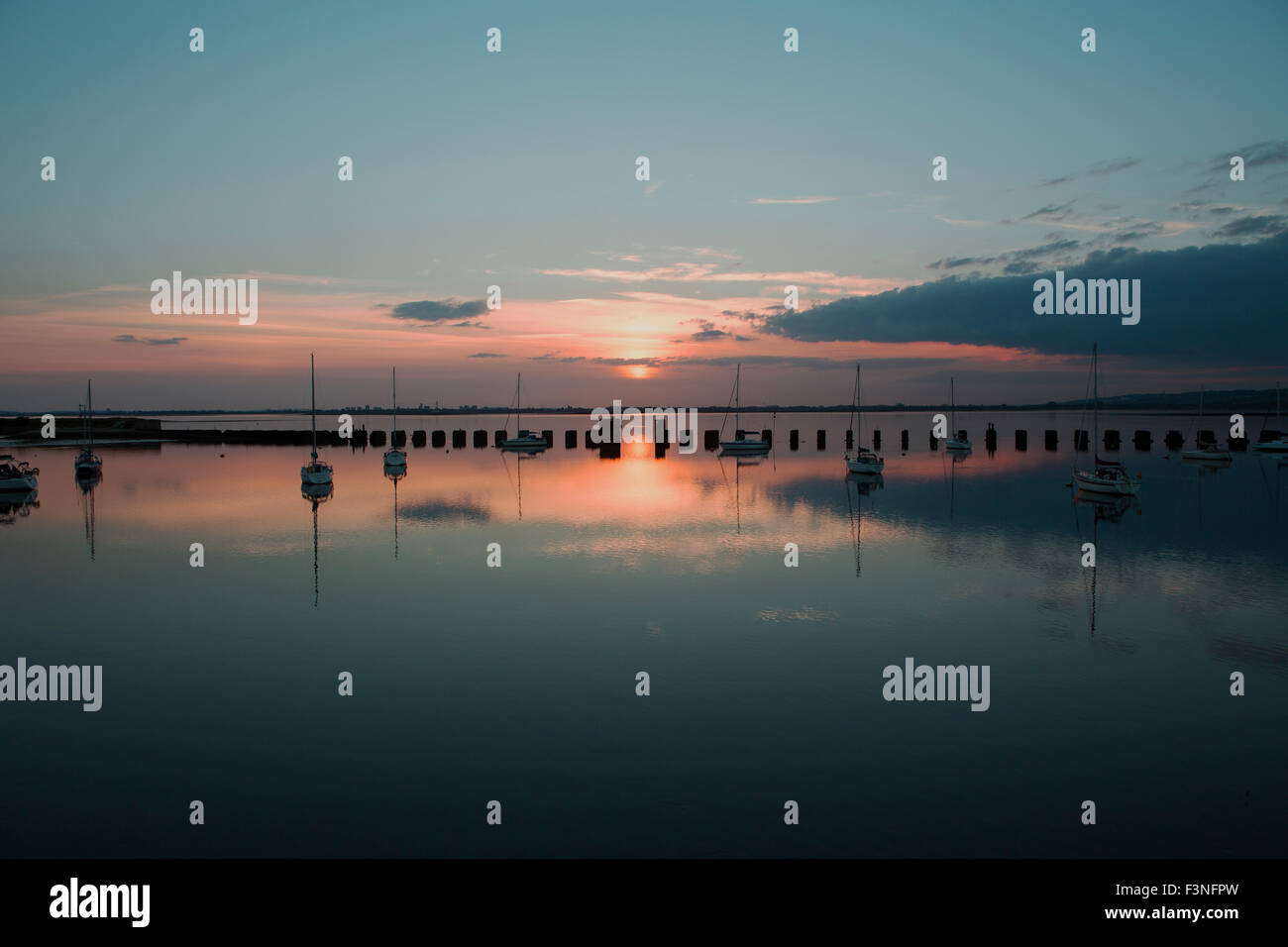 Sonnenuntergang auf der Hayling Billy-Brücke. Blick über Langstone Hafen in Richtung der untergehenden Sonne hinter Portsmouth auf einen ruhigen Abend. Stockfoto