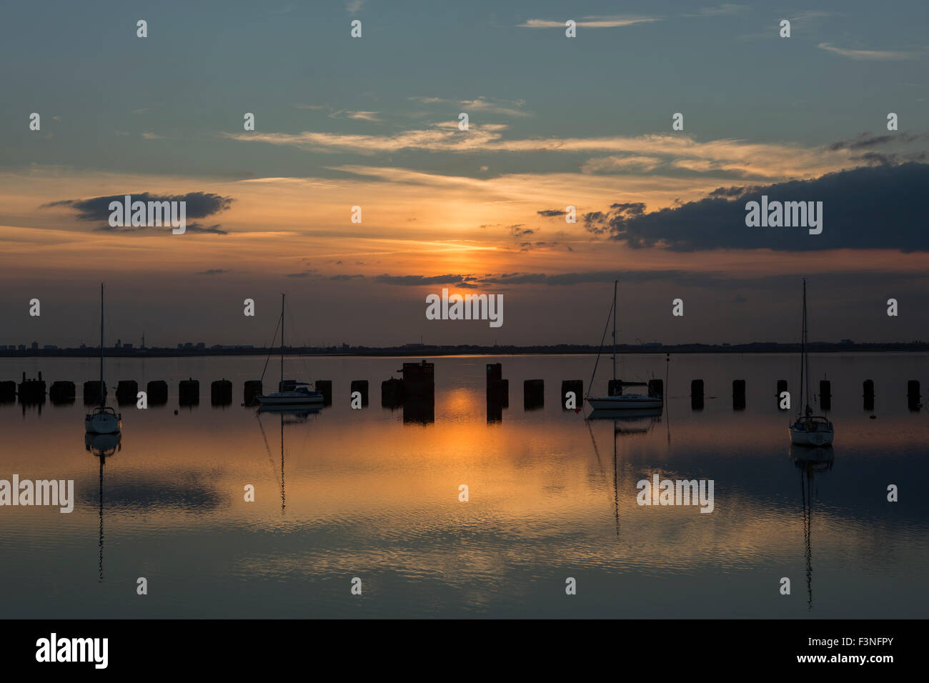 Sonnenuntergang auf der Hayling Billy-Brücke. Blick über Langstone Hafen in Richtung der untergehenden Sonne hinter Portsmouth auf einen ruhigen Abend. Stockfoto