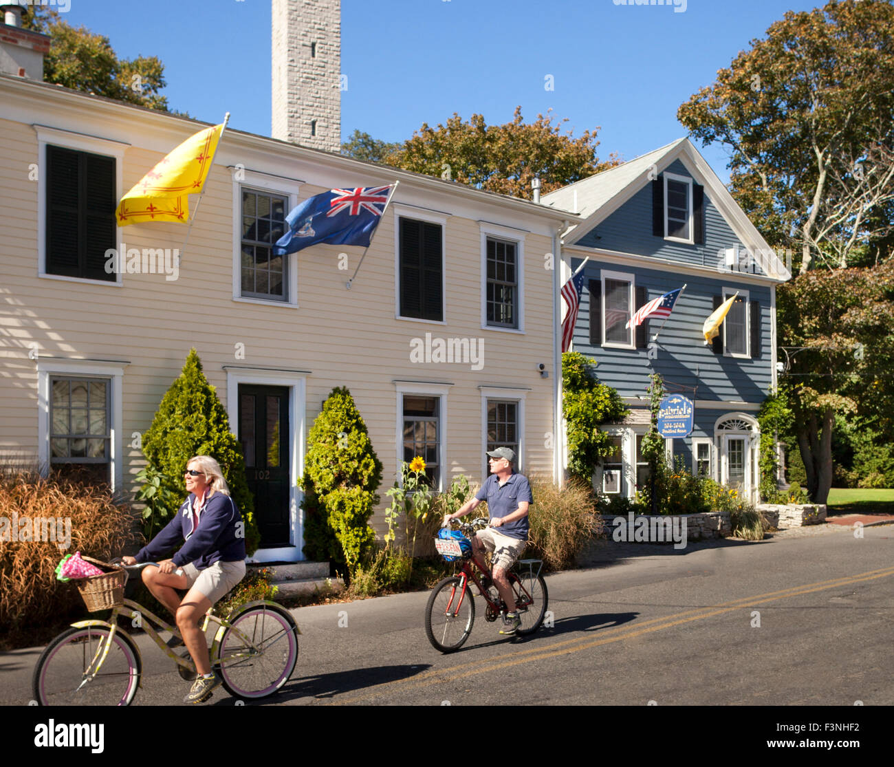 Paar Biken vor Gabriels Bed And Breakfast mit Pilgrim Monument im Hintergrund, Provincetown, Massachusetts, USA Stockfoto Paar Biken vor Gabriels Bed And Breakfast mit Pilgrim Monument im Hintergrund, Provincetown, Massachusetts, USA Stockfoto