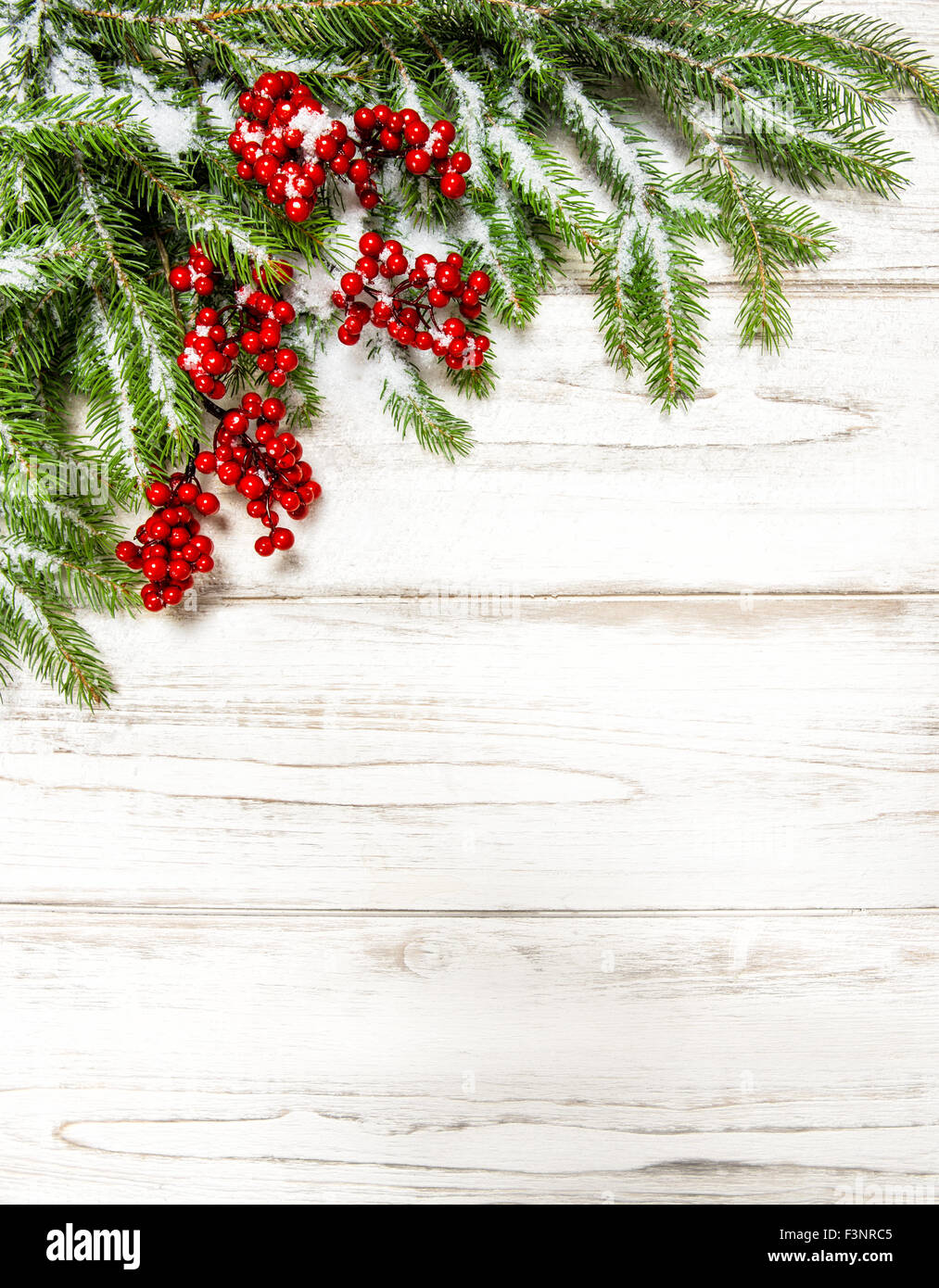 Weihnachtsbaum Zweig mit roten Beeren auf hölzernen Hintergrund. Winter Urlaub Dekoration Stockfoto