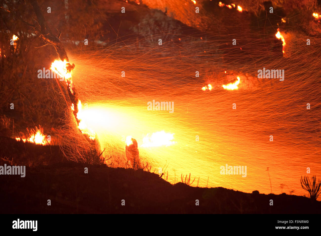 Streifen von Funkenflug Feuer und brennenden Baum Zweige Afterglow in der Nacht. Platy Dorf brennenden Website. Insel Limnos, Griechenland Stockfoto